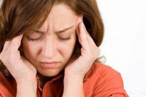 woman with headache holds temples