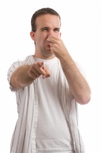 man squeezing his nose and pointing indicating bad smell